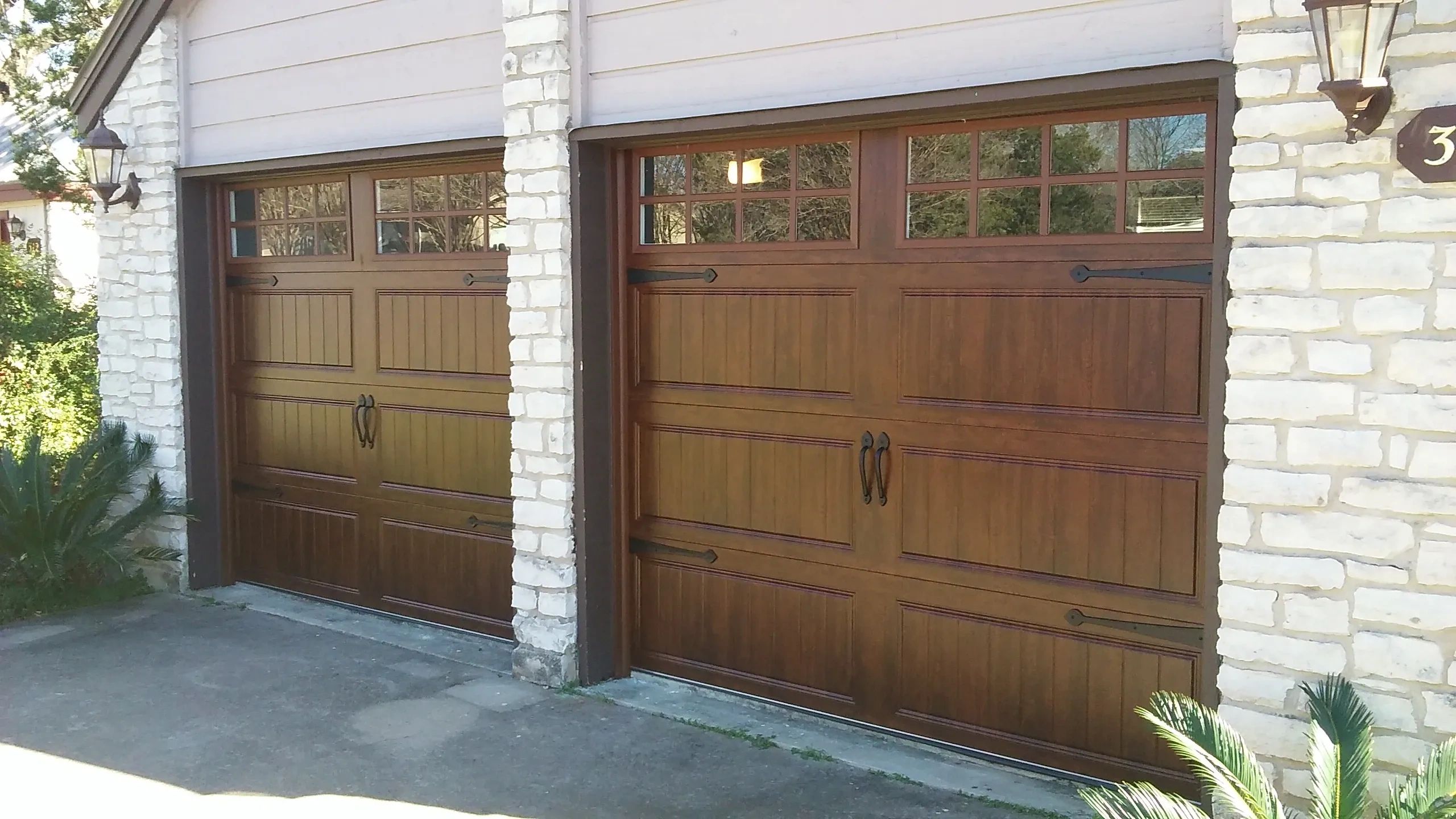 Two wooden garage doors with decorative handles and windows at the top.