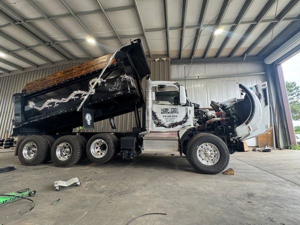 Large dump truck with raised bed inside a warehouse.