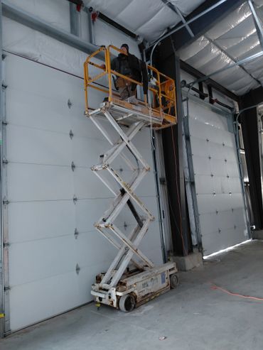 Worker on a scissor lift inside a large industrial garage.