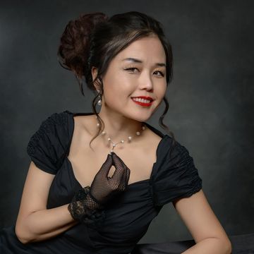 Elegant woman in black dress and lace gloves with pearl necklace.