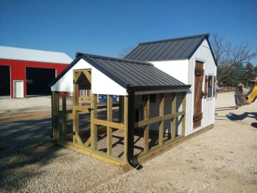 A small white and black chicken coop with an enclosed area outside.