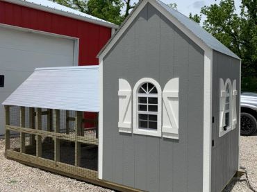 A small gray and white chicken coop with a fenced area.