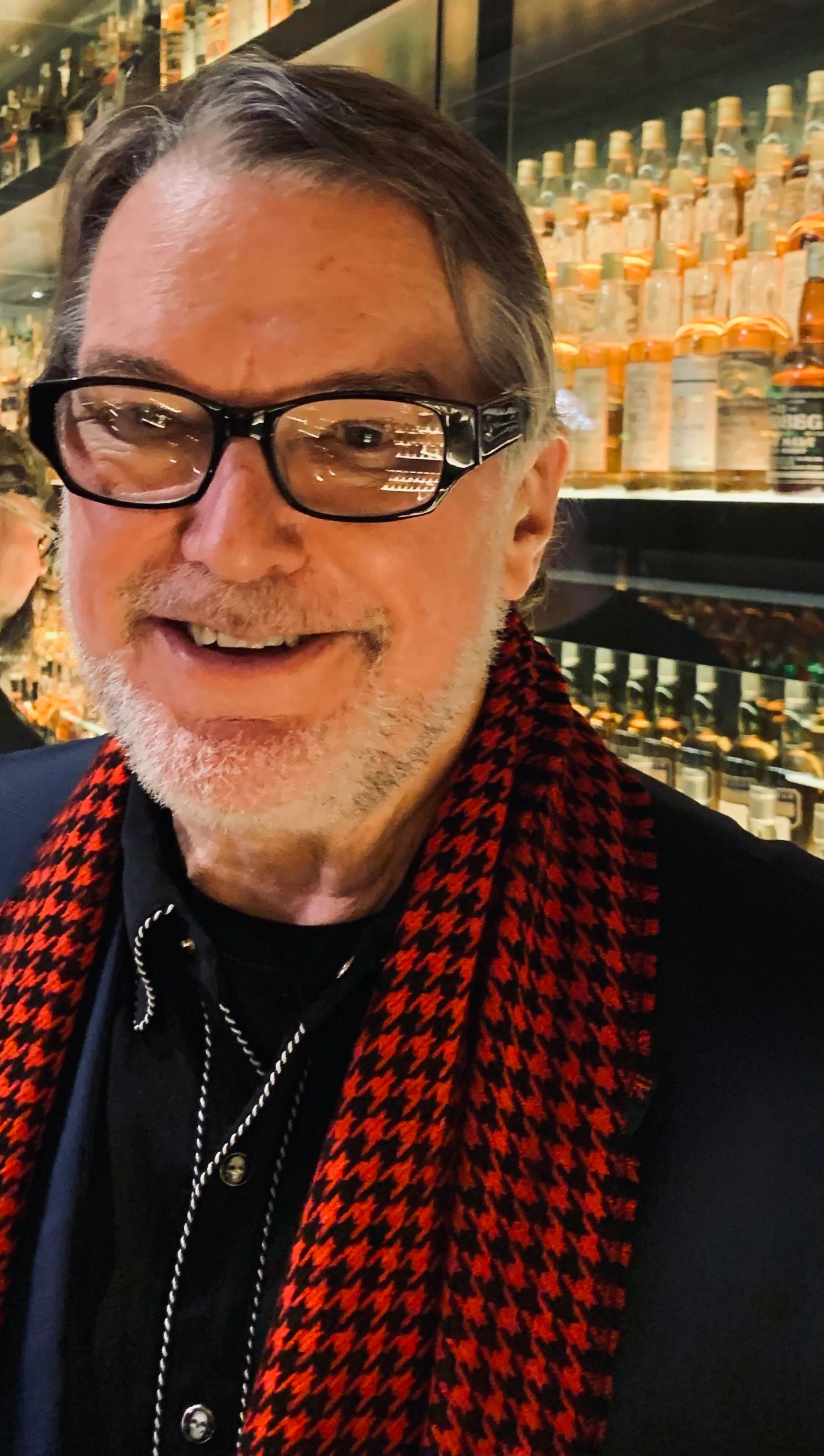 Nick Spill surrounded by whiskey bottles in Edinburgh, Scotland.