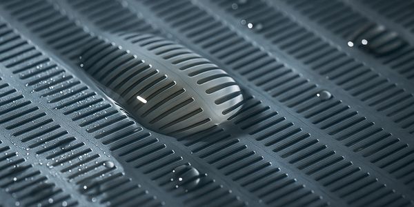 Close-up of water droplets on a textured, ribbed surface with a cool blue tone.