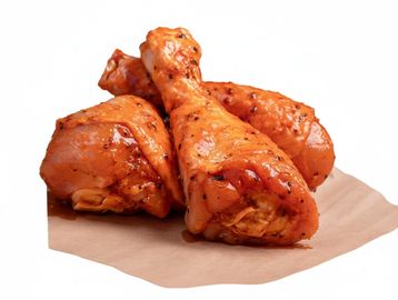 Three glazed chicken drumsticks on parchment paper.