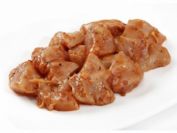 Marinated chicken pieces coated with spices on a white plate.