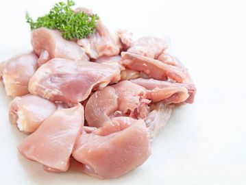 Raw chicken pieces arranged with a sprig of parsley on top.