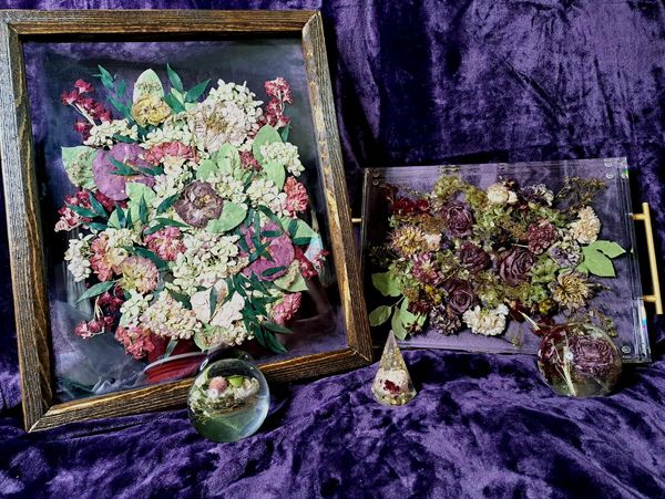 Dried floral art and decorative pieces on purple fabric.