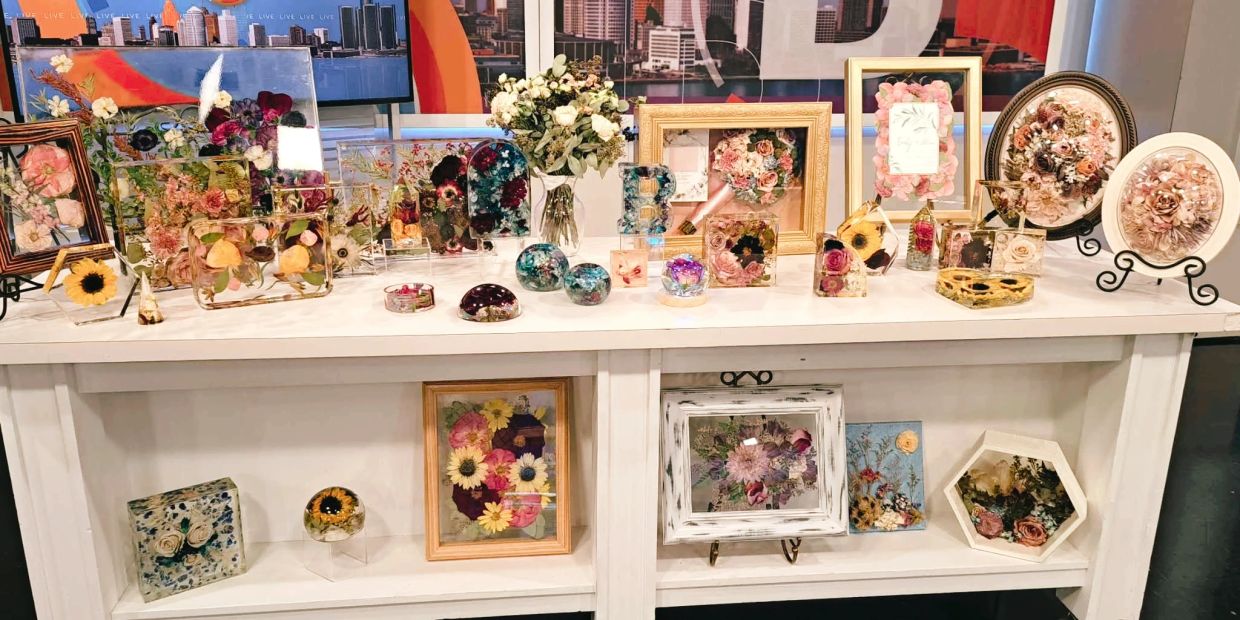 Table display of various floral art pieces and decorations.