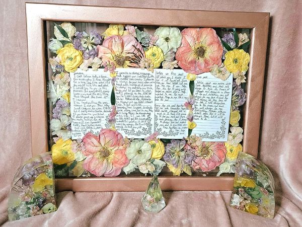 Framed letter surrounded by pressed flowers and decorative blocks.