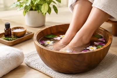 Traditional foot spa - feet soaking in a wooden bowl with flowers at AA Foot Spa & Massage in Puyall