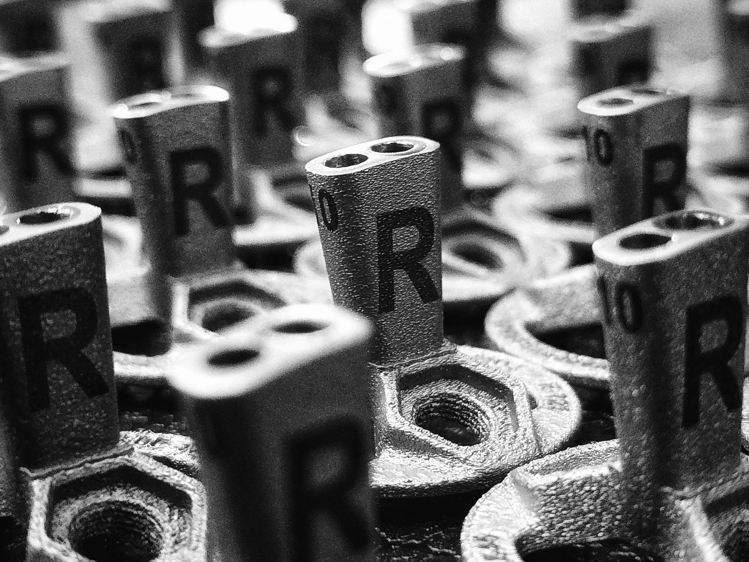 Close-up of metal connectors labeled 'R' and hexagonal bolts in black and white.
