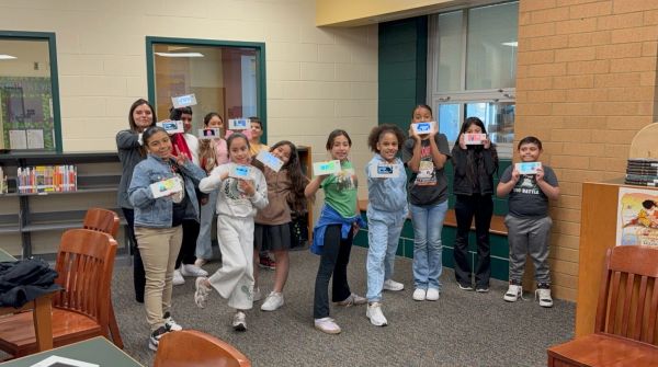 Group of children holding cards in a library.