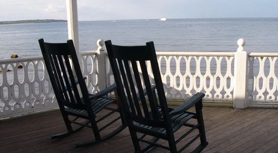 Two rocking chairs on a porch overlooking the ocean.