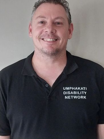 Man smiling wearing a black polo shirt with logo.