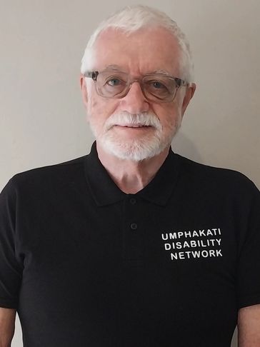 Elderly man wearing glasses and a black shirt with 'Umphakati Disability Network' text.