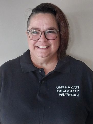 Person smiling wearing a black polo shirt with 'Umphakatsi Disability Network' text.