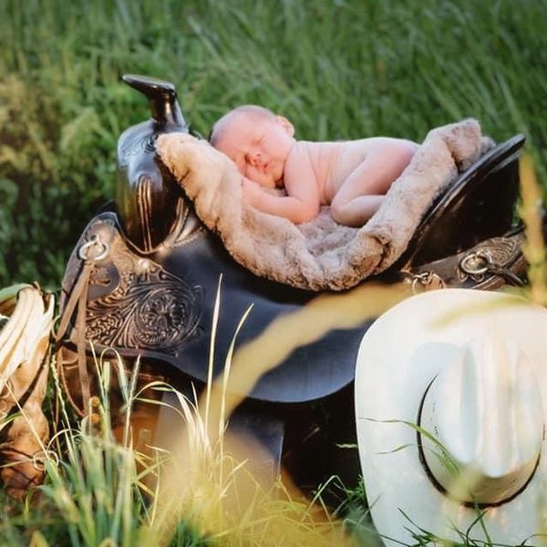 newborn baby laying on a saddle 