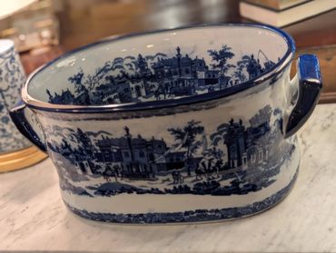 Blue and white ceramic container with scenic countryside design.
