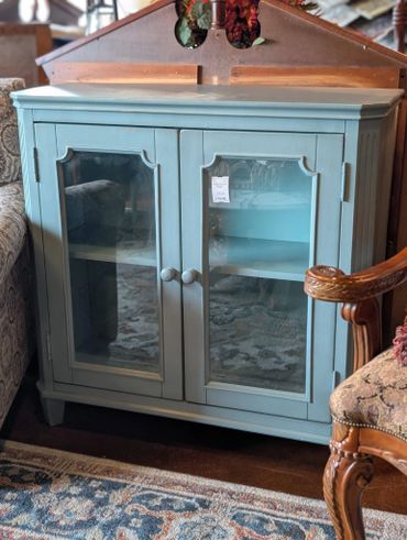 Blue wooden cabinet with glass doors in a cozy room.
