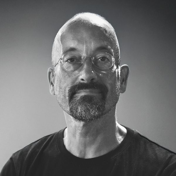 Black and white portrait of a bald man with glasses and a goatee.