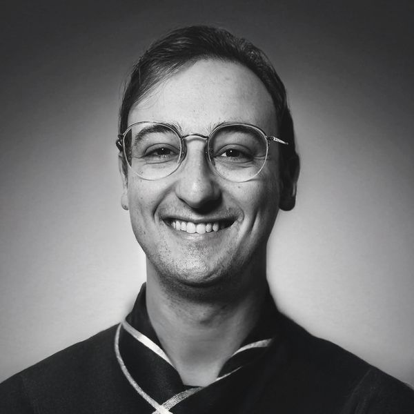 Smiling man wearing glasses in a black and white portrait.