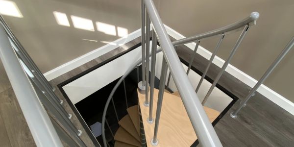 Modern spiral staircase with metal railings and wooden steps inside a home.