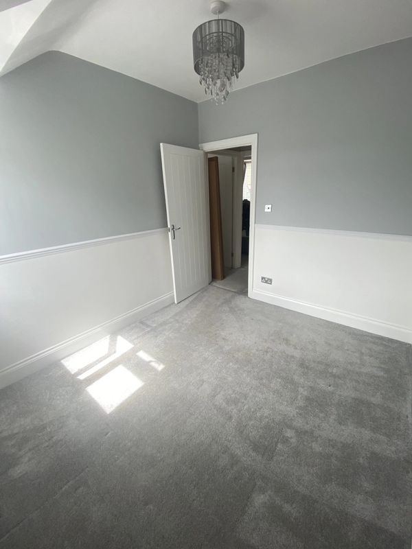 Empty room with grey carpet and light grey walls, white trim, and a chandelier.