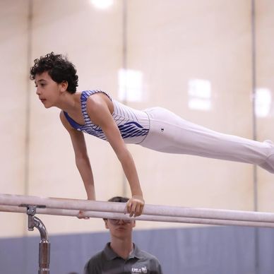 Young gymnast performing a hold on parallel bars.