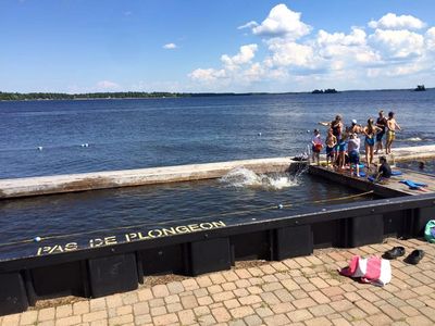 People enjoy a sunny day by the water near a no diving pool area.