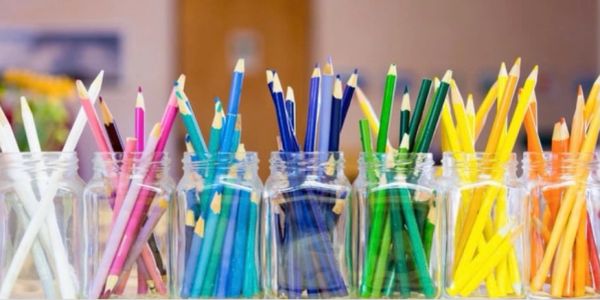 Colored pencils sorted by color in glass jars.