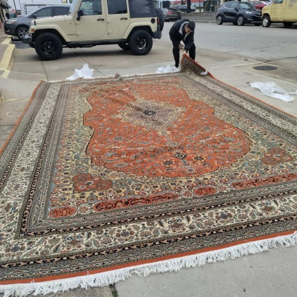 Tom inspecting a beautiful oriental rug spread out before Rug repair and Rug Cleaning.