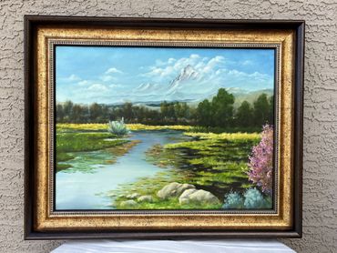 Tranquil creek surrounded by green grass and blue skies and clouds backdrop