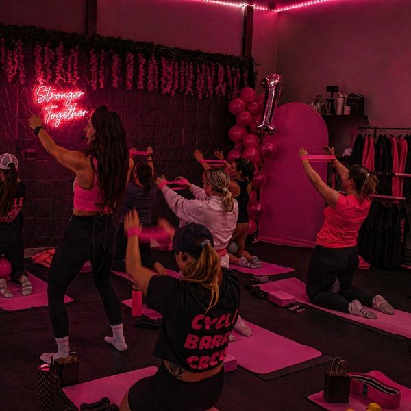 Women exercising together in a pink-themed fitness class.