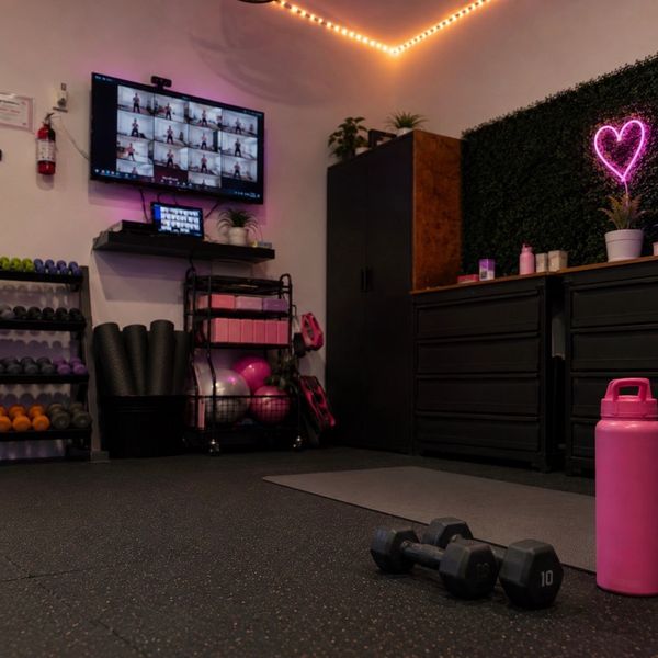 Home gym with weights, yoga mats, and a virtual workout on screen.