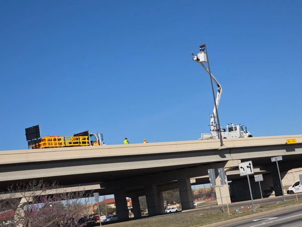 Construction workers on highway overpass.