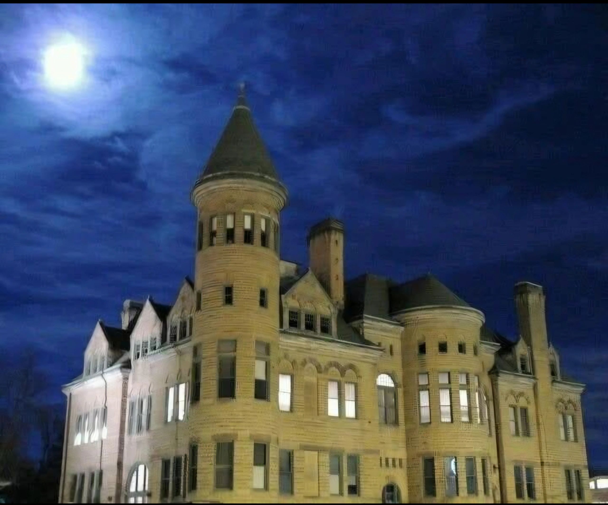 Historic castle under a bright full moon at night.