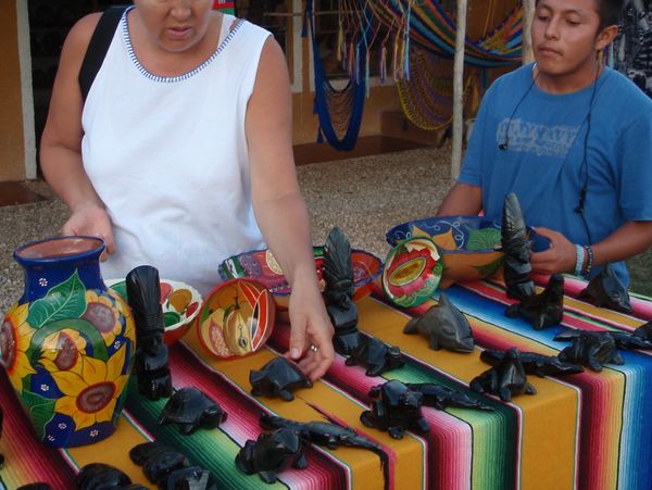 Handling the colorful ceramics and sculptures at an outdoor table.