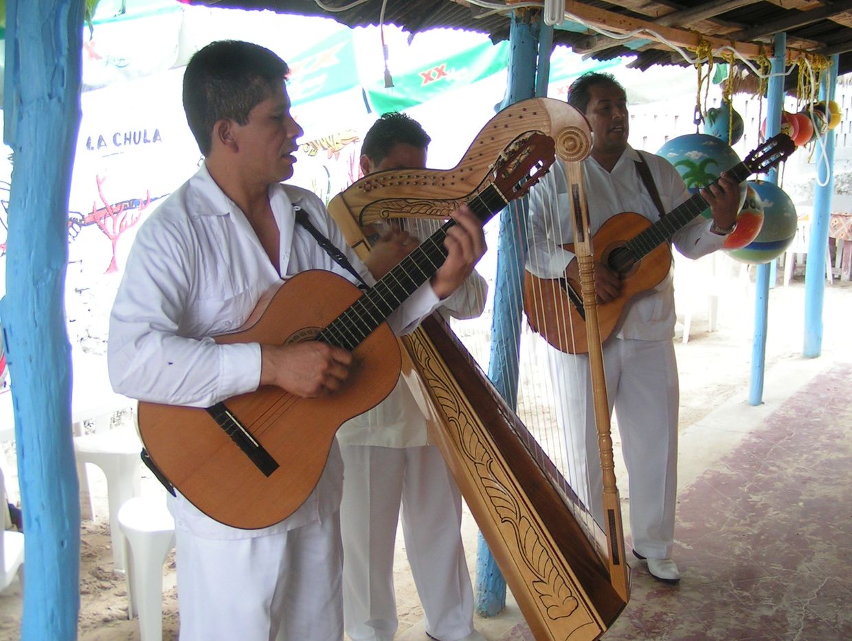 Men playing two guitars and a harp on a patio.