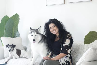 Woman with two dogs on a white couch.