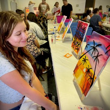 Woman admiring paintings at a group art event.