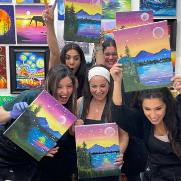 Group of women proudly holding landscape paintings.