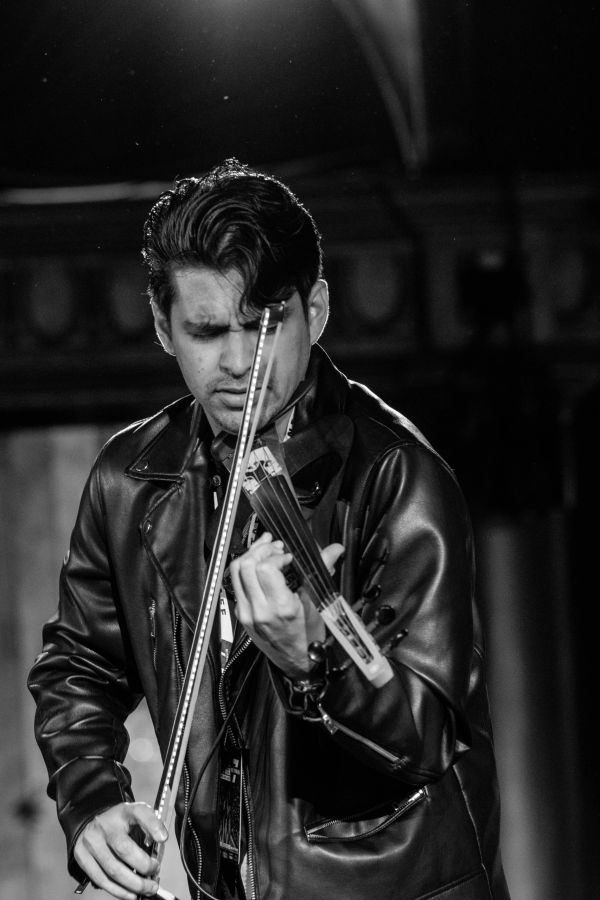 Man in leather jacket passionately playing violin.