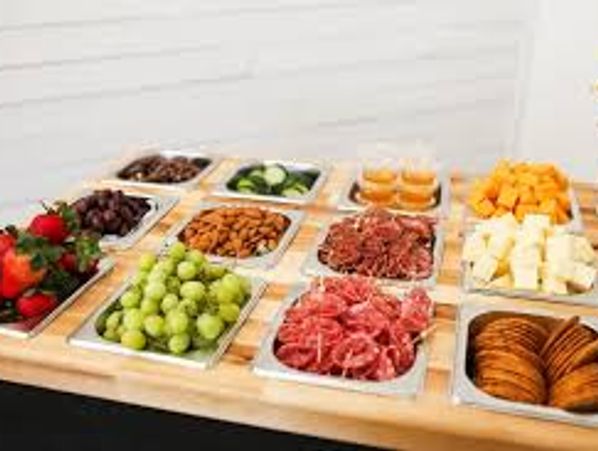 A table with assorted fruits, nuts, cheese, and crackers arranged in trays.