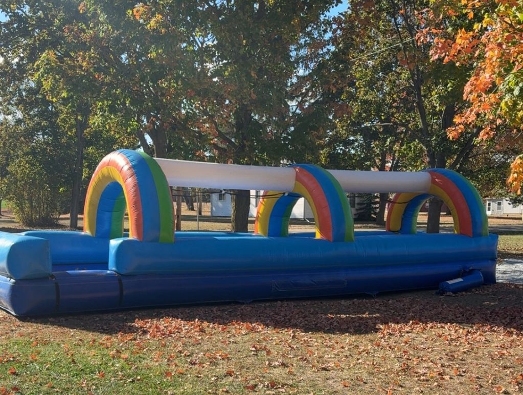 Colorful inflatable slip-and-slide on a grassy lawn with autumn leaves.