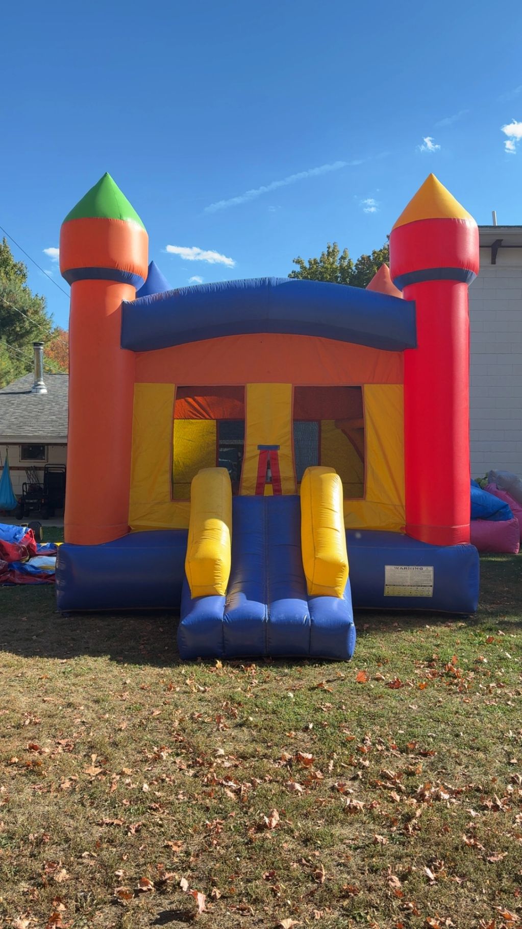 Colorful inflatable bounce house with slide on a grassy lawn.