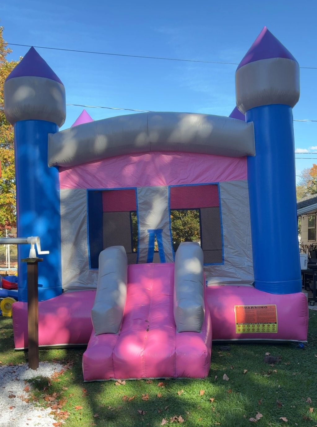 Pink and blue inflatable bounce house castle in a backyard.