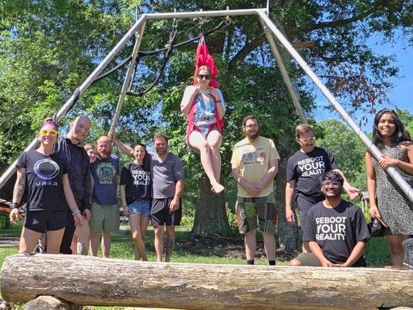 Group poses outdoors, one person in red swing.