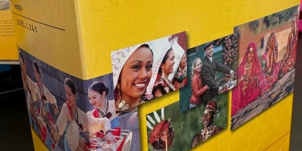 Stacked yellow Rosetta Stone software boxes featuring photos of people from cultures around the worl