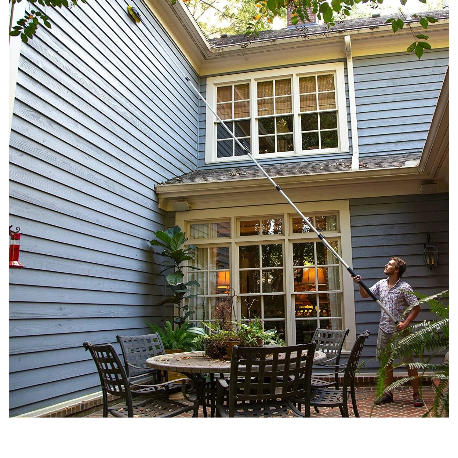 A person using soft wash to wash and clean siding of his house